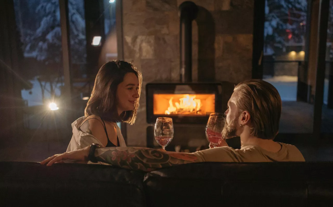 Paar mit Weingläser vorm Kamin